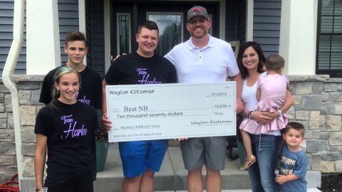 Waylon Klitzman delivers a $10,000 check to cancer patient Harlow Phillips' family.