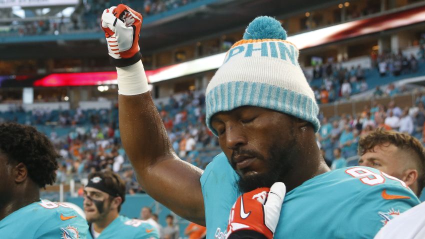 Miami Dolphins defensive end Robert Quinn (94) raises his right fist during the singing of the national anthem, before the team's NFL preseason football game against the Tampa Bay Buccaneers, Thursday, Aug. 9, 2018, in Miami Gardens, Fla. (AP Photo/Wilfredo Lee)