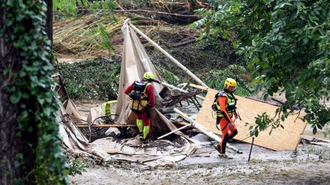 Rescuers walk past a damaged tent in Saint-Julien-de-Peyrolas.
