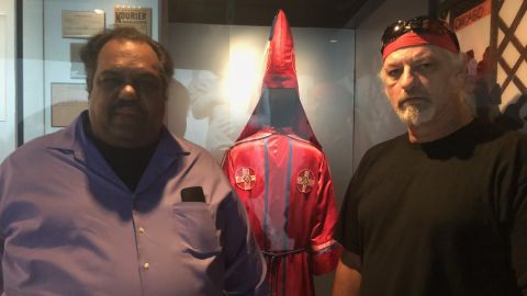 Daryl Davis and Richard Preston pose in front of an old KKK robe and hood at the museum.
