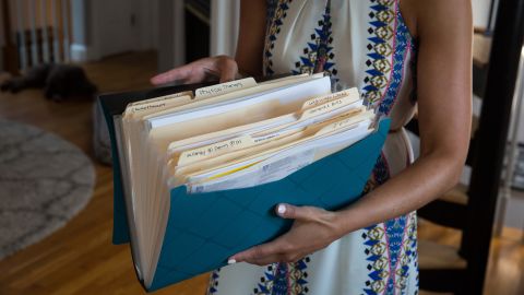 Kate Weissman displays her "cancer folder" containing the paperwork involved in her treatment and battle with her insurance company.