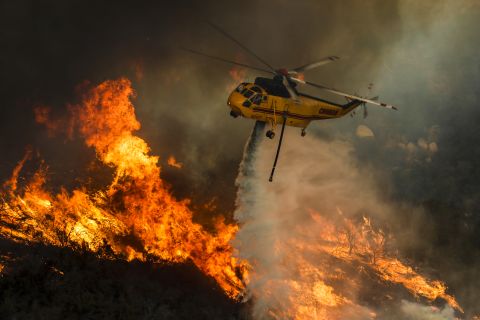 A helicopter drops water on flames in Lake Elsinore, California, on Friday, August 10.