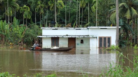 An Indian man steers his boat past houses immersed in flood waters in Kochi, in Kerala state, on Friday.
