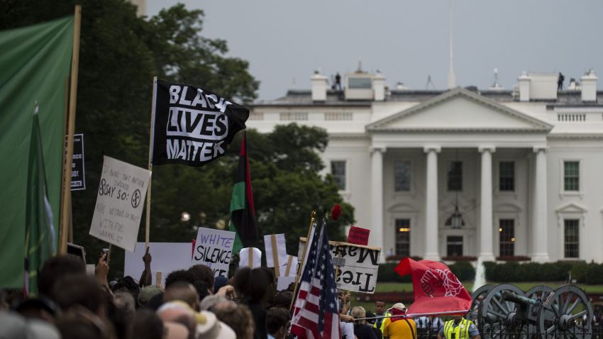 Demonstrators opposed to a far-right rally hold posters and banners in front of the White House August 12, 2018 in Washington, DC, one year after the deadly violence at a similar protest in Charlottesville, Virginia. - Last year's protests in Charlottesville, Virginia, that left one person dead and dozens injured, saw hundreds of neo-Nazi sympathizers, accompanied by rifle-carrying men, yelling white nationalist slogans and wielding flaming torches in scenes eerily reminiscent of racist rallies held in America's South before the Civil Rights movement. (Photo by Eric BARADAT / AFP)        (Photo credit should read ERIC BARADAT/AFP/Getty Images)