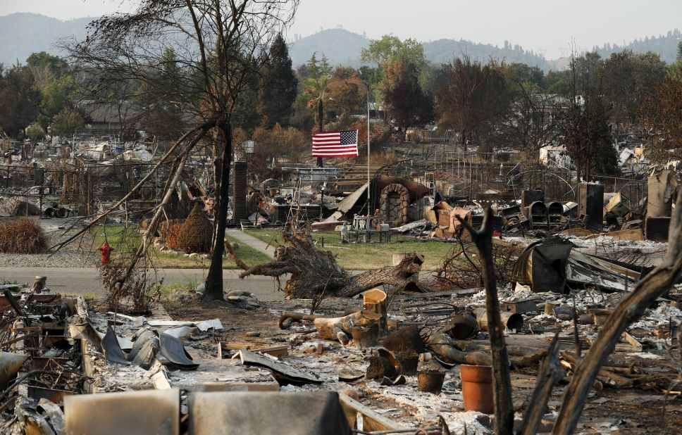 A flag flies at half-staff amid the rubble of homes burned in the Carr Fire, on Sunday, August 12.