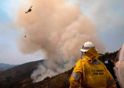 A firefighter watches a helicopter drop water at the Holy Fire in Lake Elsinore Saturday.