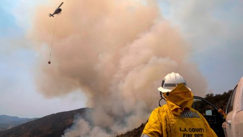A firefighter watches a helicopter drop water at the Holy Fire in Lake Elsinore Saturday.