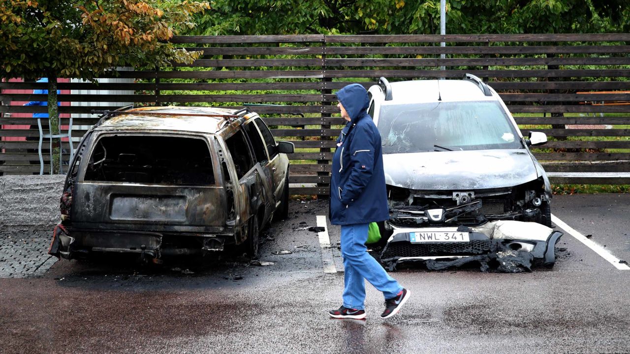 A person walks past burned cars parked at Frölunda Square in Gothenburg, Sweden, on Tuesday.