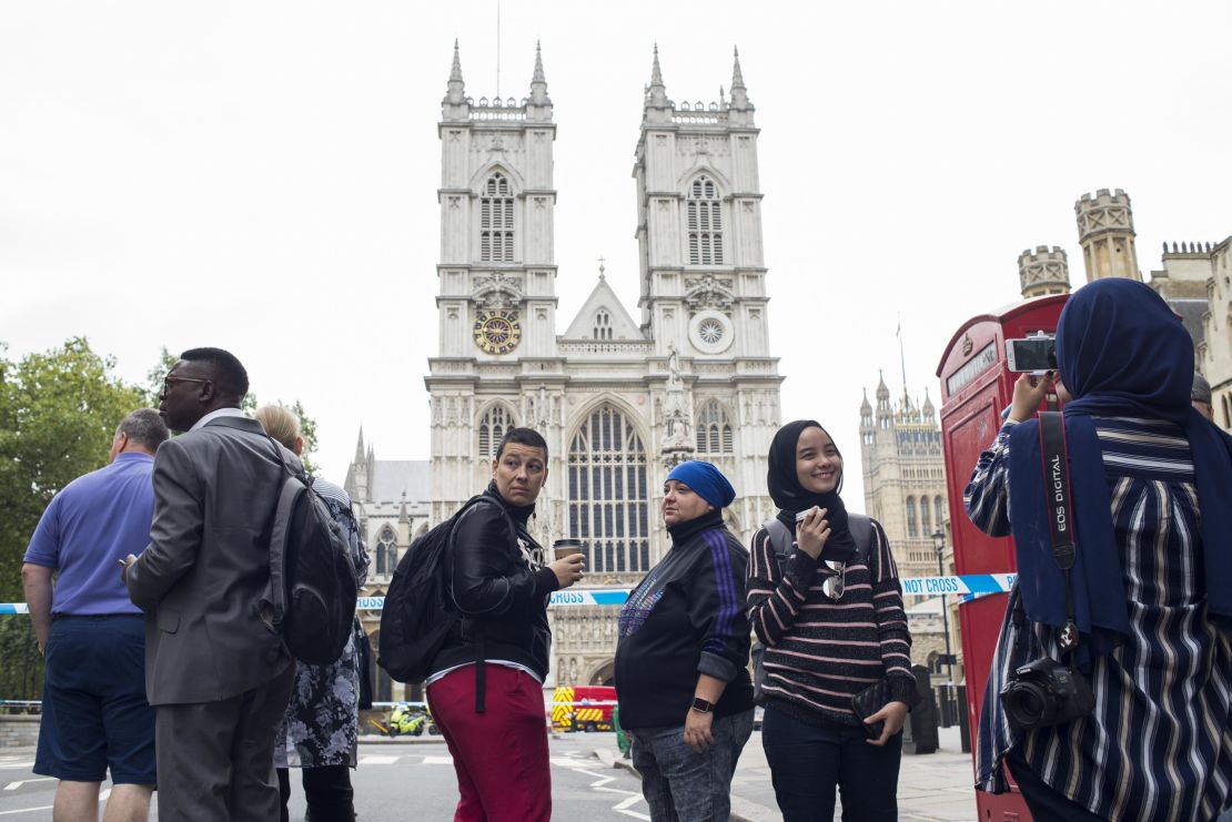 Siti Atikah Binti ABD Razak, 19, second from right, is photographed by her sister, Siti Nadhirah Binti ABD Razak, 21 (far right with back turned) outside Westminster Abbey, which was not accessible due to the ongoing police investigation.