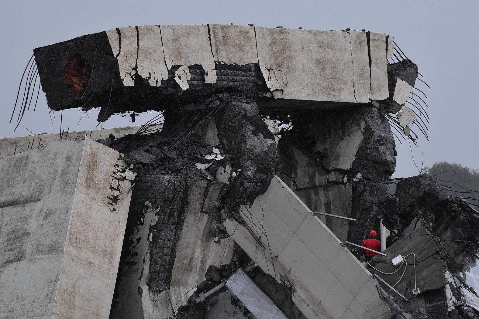 A chunk of the collapsed bridge teeters atop the rubble.