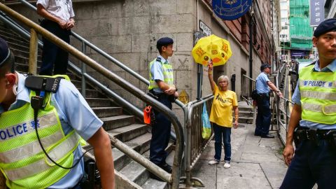 A counter-protester raises a yellow umbrella decorated with the Union flag as police officers stand guard during a demonstration by pro-China groups outside the Foreign Correspondents' Club in Hong Kong.