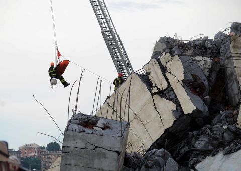 A rescuer and a stretcher are lifted above the wreckage.