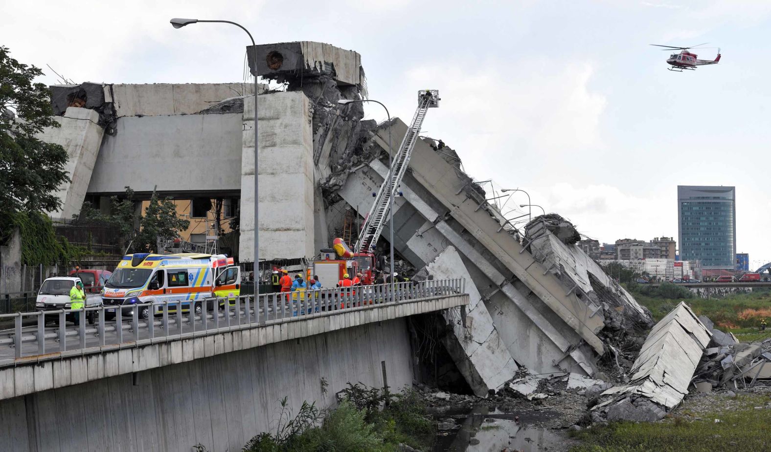 A helicopter flies over the rubble.