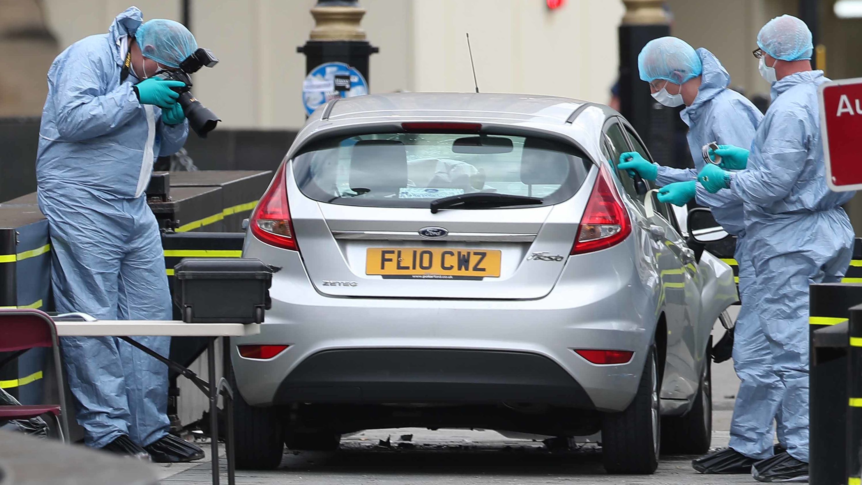 Police forensics officers work around a silver Ford Fiesta car that was driven into a barrier at the Houses of Parliament in central London on August 14.