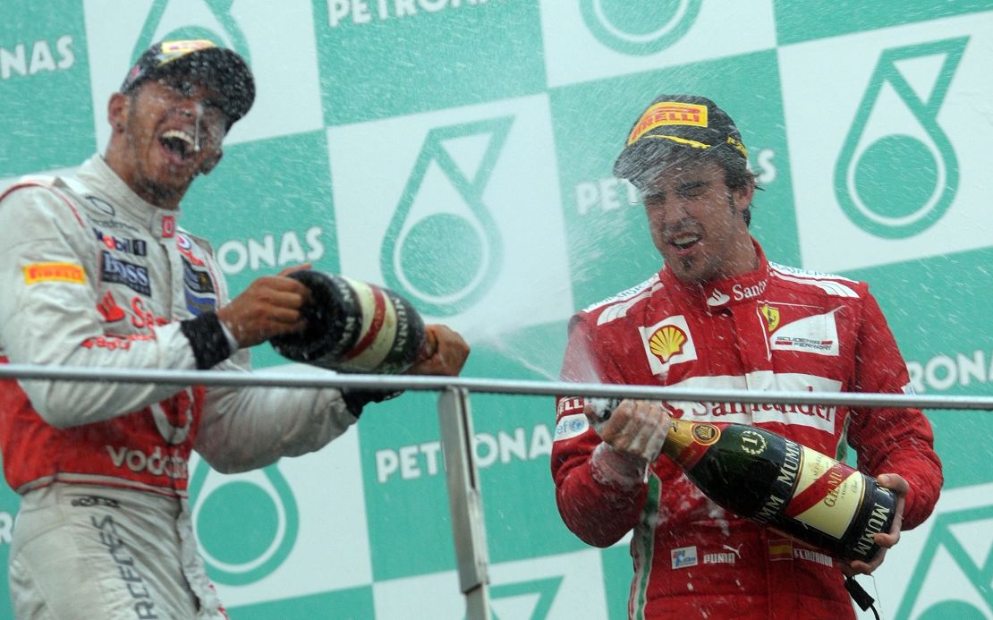 Ferrari driver Fernando Alonso of Spain (R) and McLaren-Mercedes driver Lewis Hamilton (L) of Britain celebrate on the podium with champagne after Formula One's Malaysian Grand Prix in 2012.