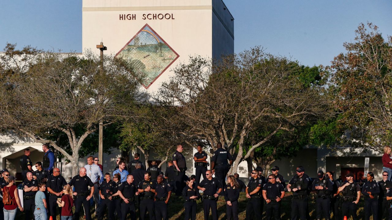 TOPSHOT - Marjory Stoneman Douglas High School staff, teachers and students return to school greeted by police and well wishers in Parkland, Florida on February 28, 2018. 
Students grieving for slain classmates prepared for an emotional return Wednesday to their Florida high school, where a mass shooting shocked the nation and led teen survivors to spur a growing movement to tighten America's gun laws. The community of Parkland, Florida, where residents were plunged into tragedy two weeks ago, steeled itself for the resumption of classes at Marjory Stoneman Douglas High School, where nearby flower-draped memorials and 17 white crosses pay tribute to the 14 students and three staff members who were murdered by a former student.
 / AFP PHOTO / RHONA WISE        (Photo credit should read RHONA WISE/AFP/Getty Images)