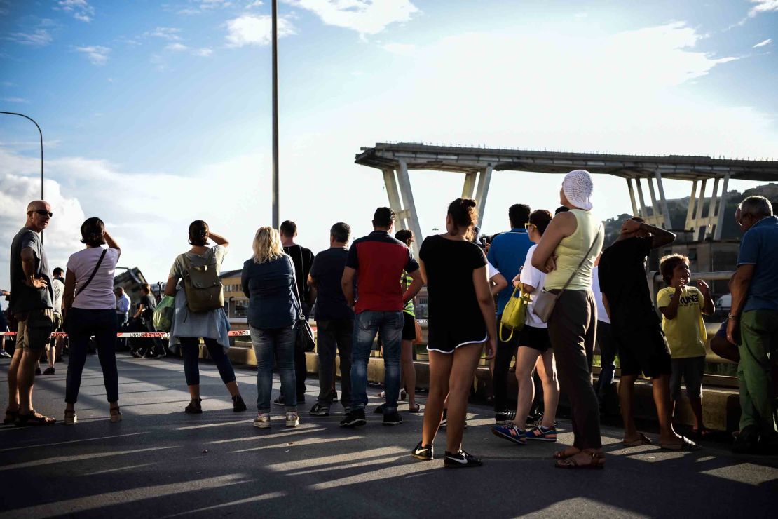 People stand looking at the Morandi motorway bridge.