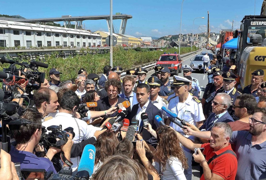 Luigi Di Maio (center right) and the transport and infrastructure minister Danilo Toninelli (center left with glasses) speak to the media in front of the collapsed bridge on Wednesday. 