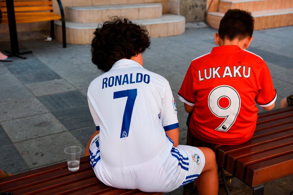 Boys wearing Real Madrid's and Manchester United jerseys sit on a bench in Skopje, Macedonia.