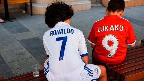 Boys wearing Real Madrid's and Manchester United jerseys sit on a bench in Skopje, Macedonia.