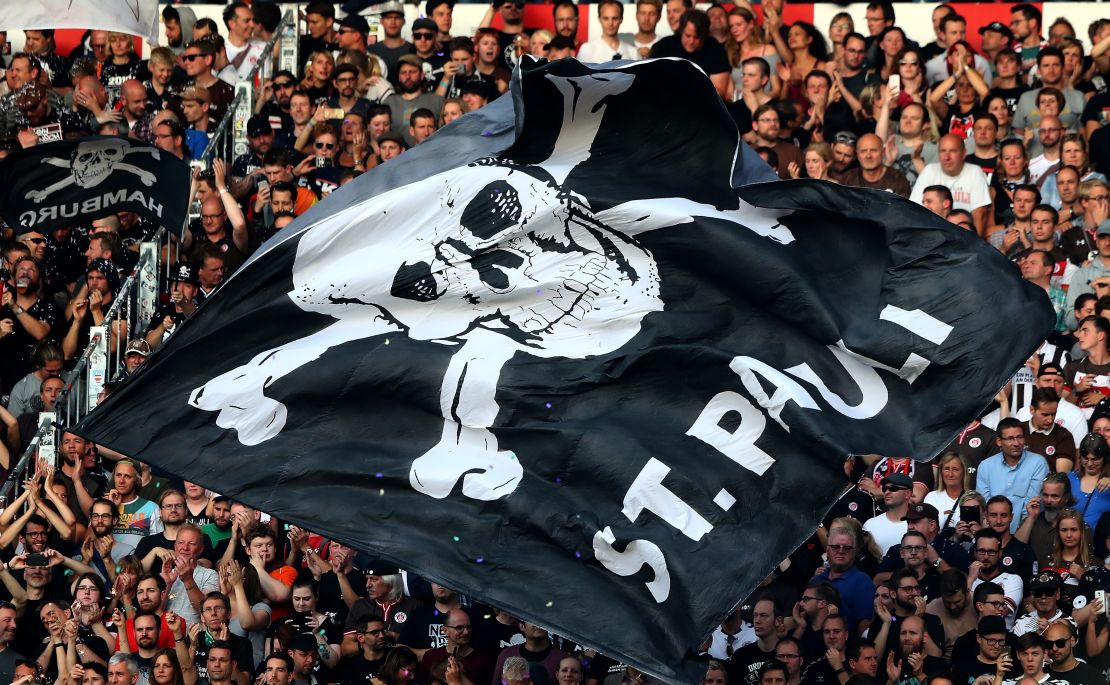 St. Pauli fans hold aloft a flag with the club's recognizable symbol.