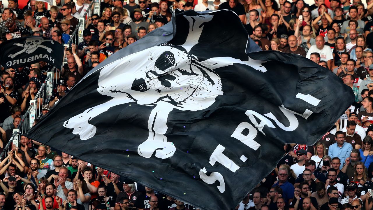 St. Pauli fans hold aloft a flag with the club's recognizable symbol.
