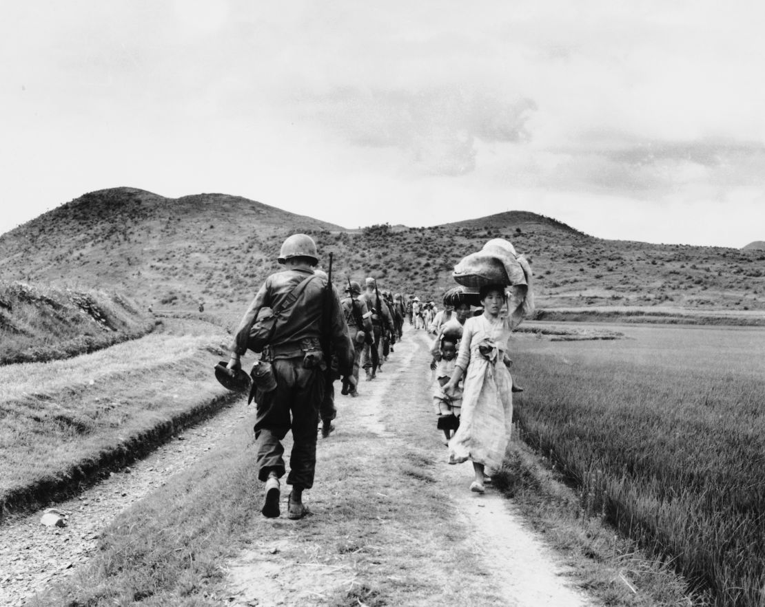 US soldiers pass fleeing refugees in the Nakdong River region, in what is now South Korea, during the Korean War.