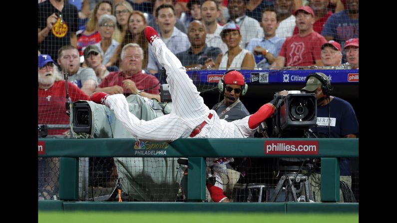 Carlos Santana of the Philadelphia Phillies falls into a camera while attempting to catch a foul ball during a baseball game against the Boston Red Sox on Tuesday, August 14, in Philadelphia, Pennsylvania. The Red Sox won 2-1.