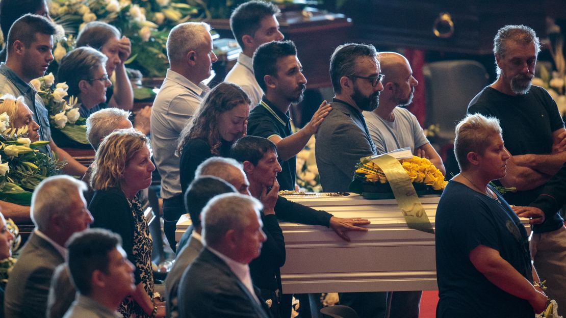 Mourners grieve during the funeral service at a Genoa convention center.