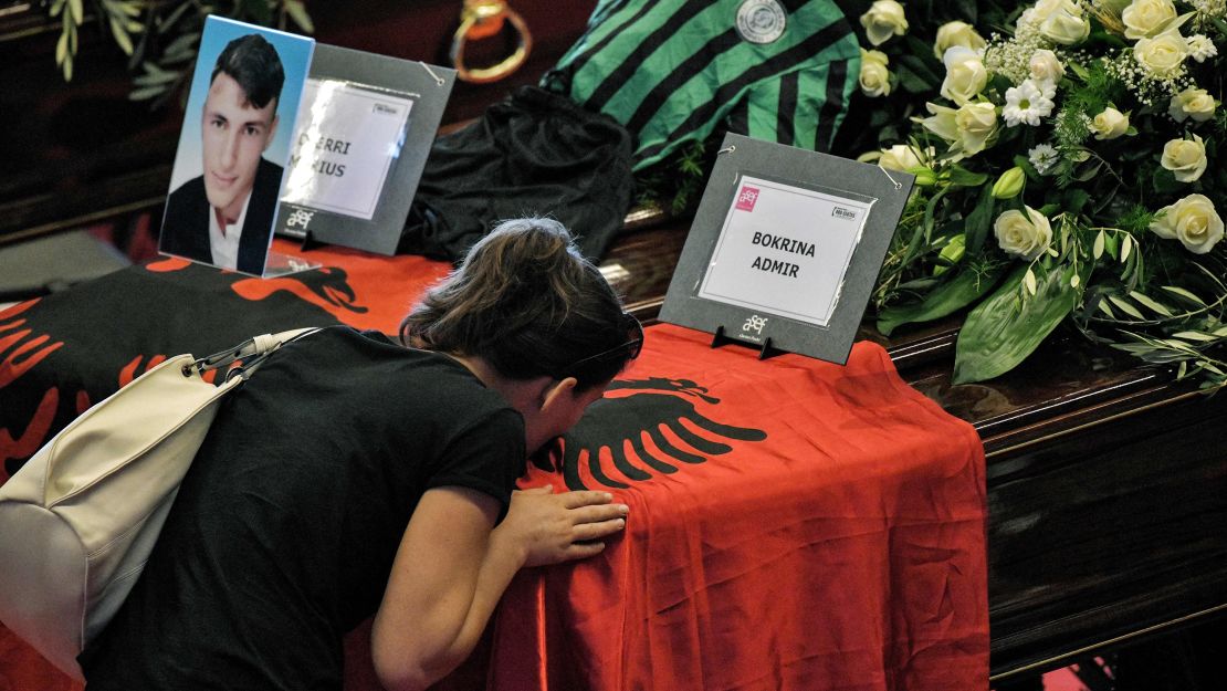 A relative of an Albanian victim kisses the flag covering the coffin ahead of the funeral service in Genoa.