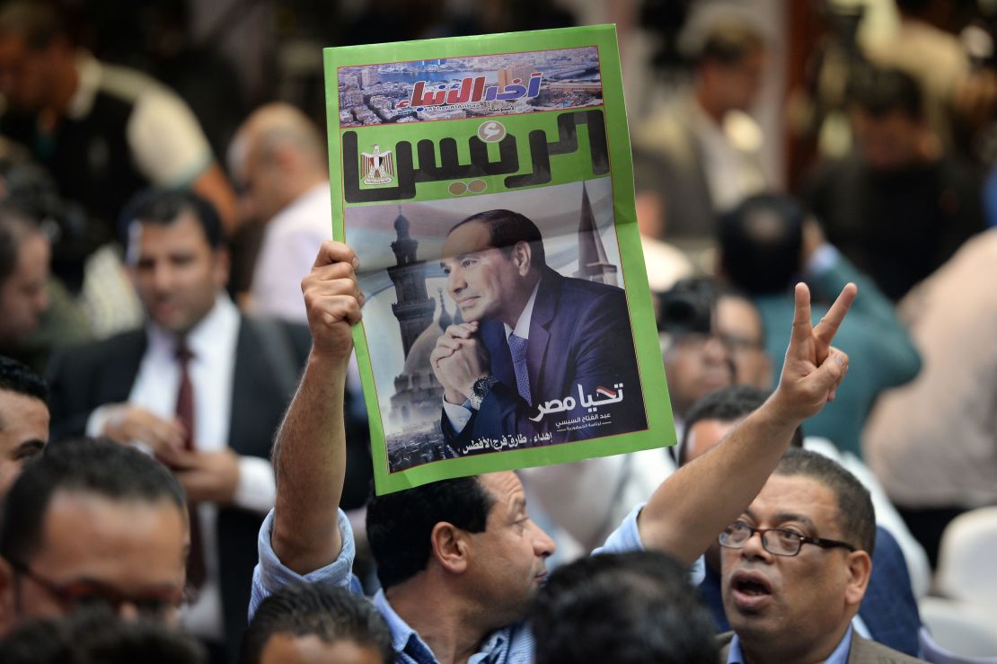A man carries a newspaper bearing the portrait of President Sisi in Cairo on April 2.