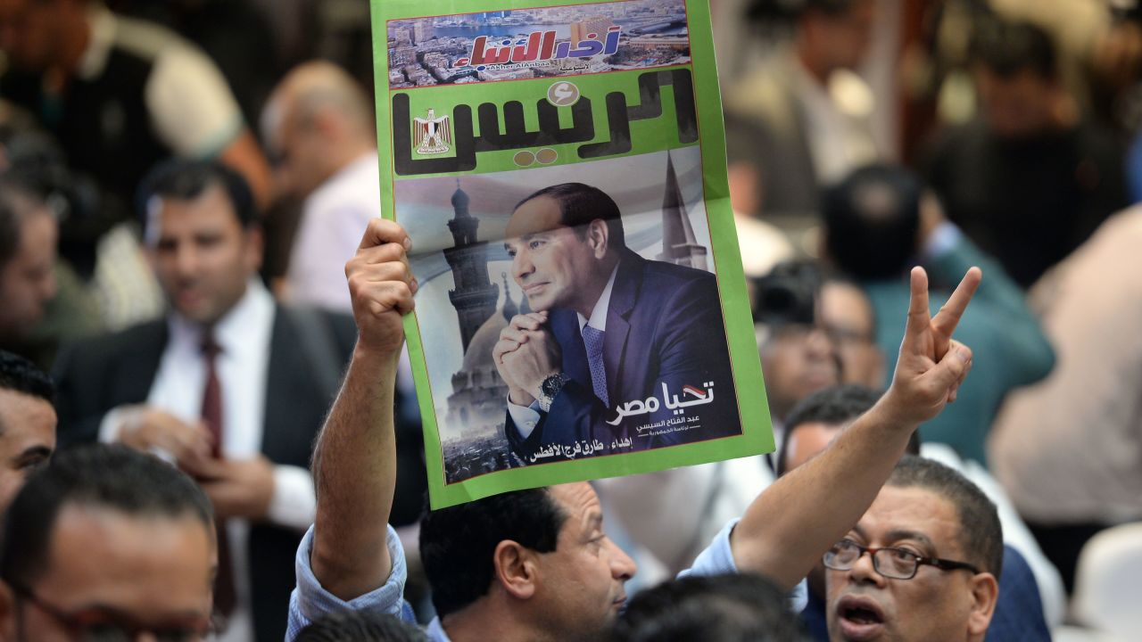 An Egyptian man carries a copy of a newspaper, bearing the portrait of Egyptian President Abdel Fattah el-Sisi in Cairo on April 2, 2018.