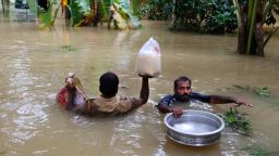 An Indian policeman, left, and a volunteer carry essential supplies for stranded people in a flooded area in Chengannur in the southern state of Kerala, India, Sunday, August 19.