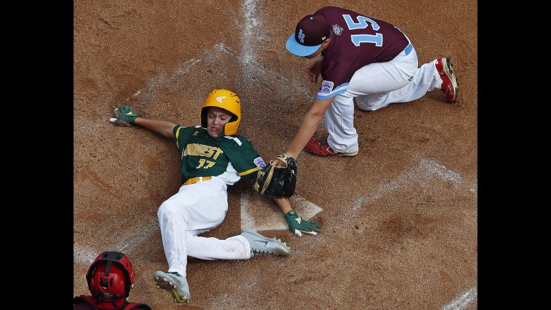 Alex Stewart of Des Moines, Iowa, scores under the tag by Logan Lama of Coventry, Rhode Island, in the fourth inning of a Little League World Series tournament game in South Williamsport, Pennsylvania, on Saturday, August 18. Upon review, the umpire's safe call was upheld.