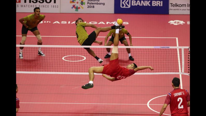 Thailand's Pornchai Kaokaew spikes the ball as Malaysia's Mohamad Azlan Alias attempts to block during a preliminary round Sepak Takraw match at the Asian Games in Jakarta, Indonesia, on Sunday, August 19.