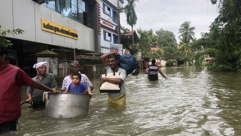 Victims of the floods wade through waist-deep water in Kerala.