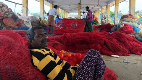 A volunteer fishermen rests on his nets in an evacuation operation in Kollam, India.