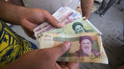 An Iraqi peddler holds in his hand banknotes of Iranian rials for exchange in the Iraqi capital Baghdad, on August 9, 2018. 