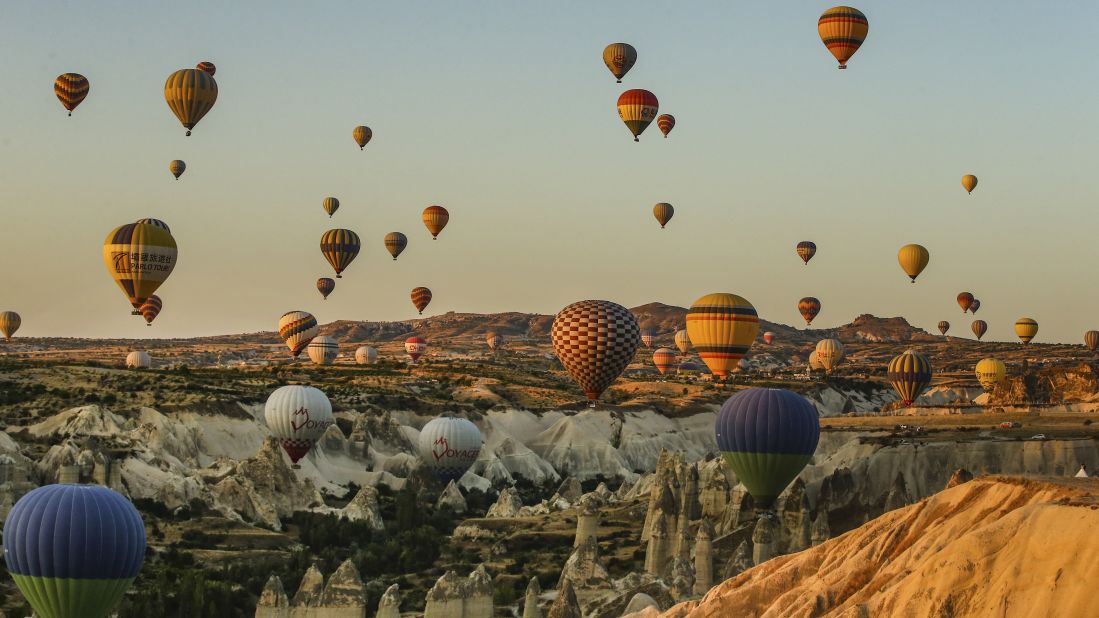 <strong>Cappadocia, Turkey: </strong>Hot-air balloons rise into the sky at sunset, allowing tourists stunning views of cone-shaped rock formations and rippled ravines. 