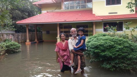 Idicula Gevarghese stands with his wife, Susamma Dikla, and granddaughter Shobita outside their flooded home in Venmony, Kerala.