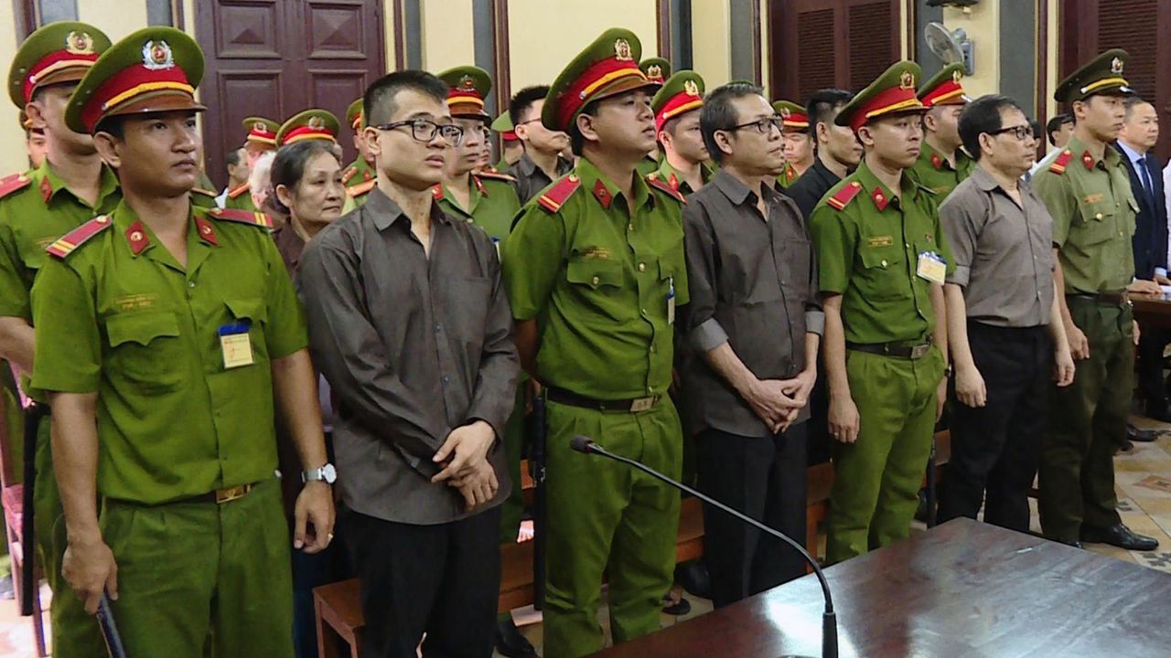 Members of California-based Provisional National Government of Vietnam stand with policemen during a trial in Ho Chi Minh city on August 22, 2018.