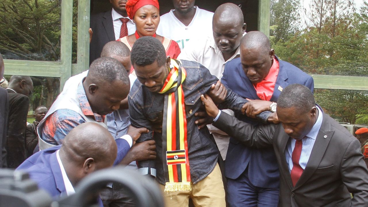Ugandan politician Robert Kyagulanyi, known as Bobi Wine, center, is helped down stairs before appearing at the general court martial in Gulu, northern Uganda on August 23, 2018.