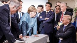 CHARLEVOIX, CANADA - JUNE 9:   In this photo provided by the German Government Press Office (BPA), German Chancellor Angela Merkel deliberates with US president Donald Trump on the sidelines of the official agenda on the second day of the G7 summit on June 9, 2018 in Charlevoix, Canada. Also pictured are (L-R) Larry Kudlow, director of the US National Economic Council, Theresa May, UK prime minister, Emmanuel Macron, French president, Angela Merkel, Yasutoshi Nishimura, Japanese deputy chief cabinet secretary, Shinzo Abe, Japan prime minister, Kazuyuki Yamazaki, Japanese senior deputy minister for foreign affairs, John Bolton, US national security adviser, and Donald Trump. Canada are hosting the leaders of the UK, Italy, the US, France, Germany and Japan for the two day summit. (Photo by Jesco Denzel/Bundesregierung via Getty Images)