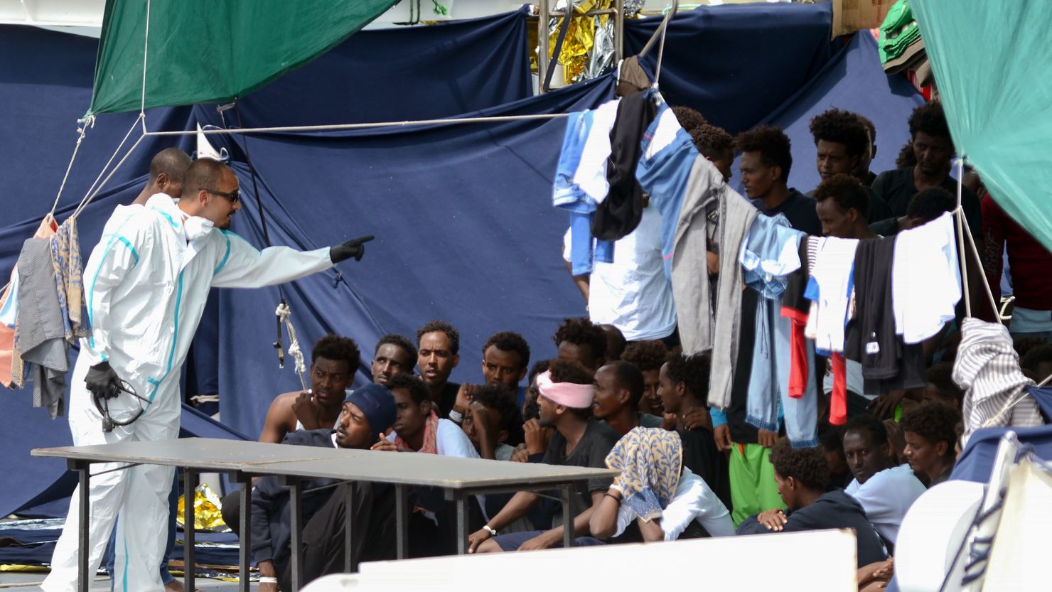 An official gestures towards migrants on the deck of the Italian Coast Guard ship Ubaldo Diciotti in the Sicilian port of Catania, on Thursday. 