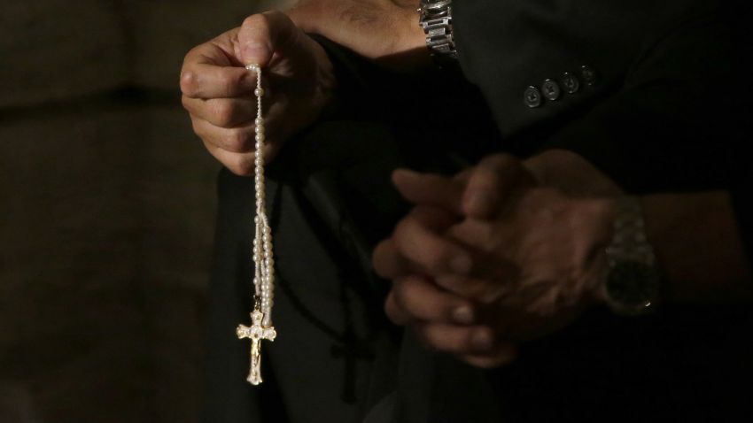 FILE- In this Sept. 24, 2015, file photo a member of the clergy prays the rosary as he waits for Pope Francis to arrive at St. Patrick's Cathedral for evening prayer service in New York. Across the U.S., Catholics once faithful with their financial support to their churches are searching for ways to respond to the constant sex-abuse scandals that have tarnished the institution in which they believe, with back-to-back scandals in the past two months. (AP Photo/Mary Altaffer, File)