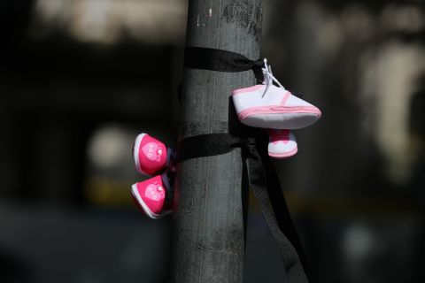 Protesters tie baby shoes to a post, signifying the children who died in mother and baby homes in Ireland, during a protest in Dublin ahead of the start of the Pope's visit to Ireland.