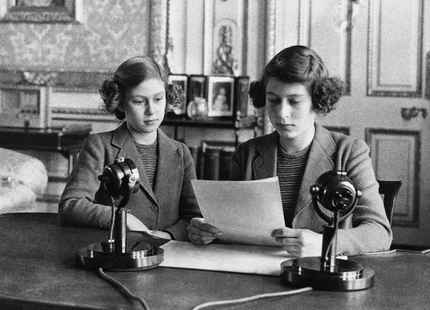 A 14-year-old Elizabeth, right, sits next to her sister for a radio broadcast on October 13, 1940. On the broadcast, her first, she said that England's children were full of cheerfulness and courage.