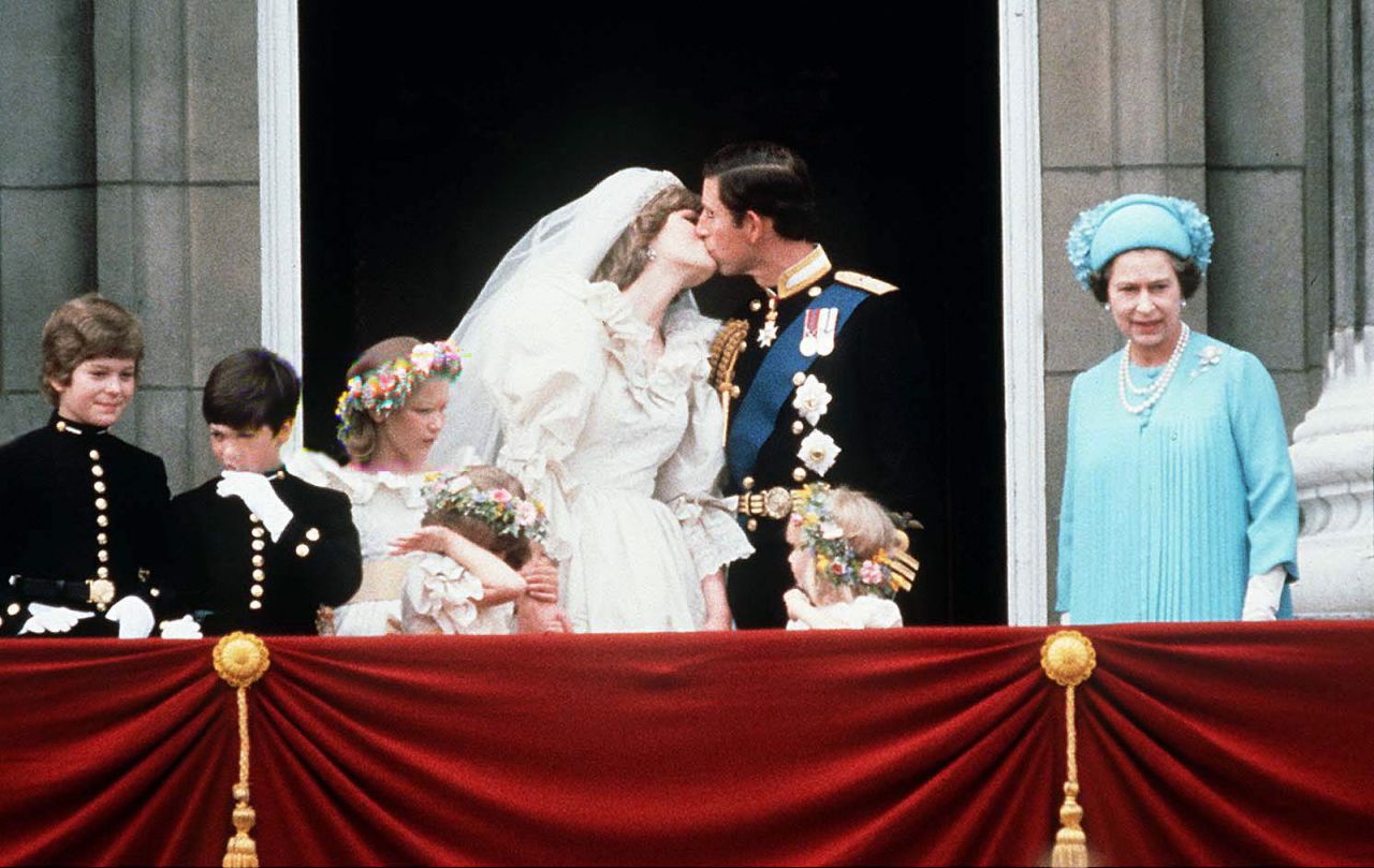 The Queen stands next to Prince Charles as he kisses his new bride, Princess Diana, on July 29, 1981.