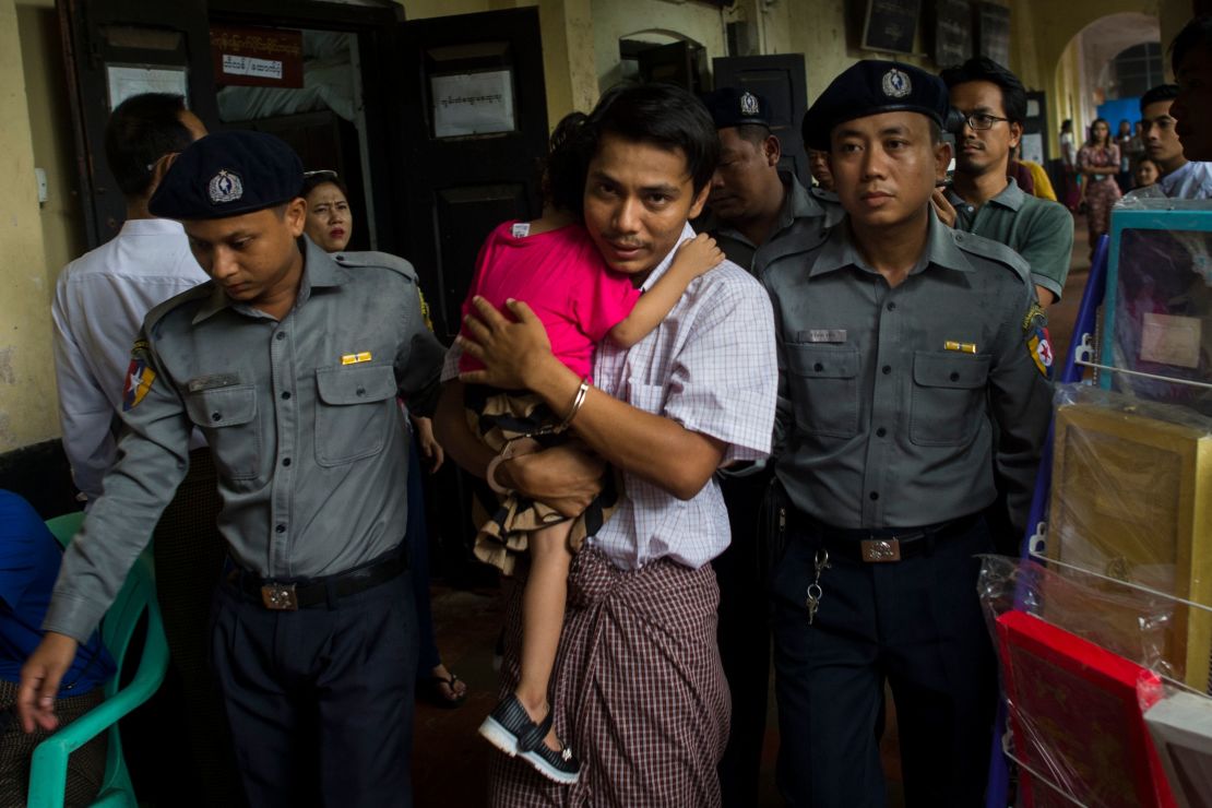 Detained Myanmar journalist Kyaw Soe Oo carries his daughter as he is escorted by police to a courtroom for his trial in Yangon last month.