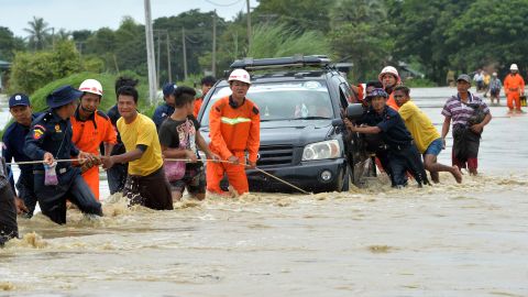 Residents negotiate a flooded road Wednesday after rampaging waters from the Swar Chaung dam spillway submerged villages in the Bago region of central Myanmar.